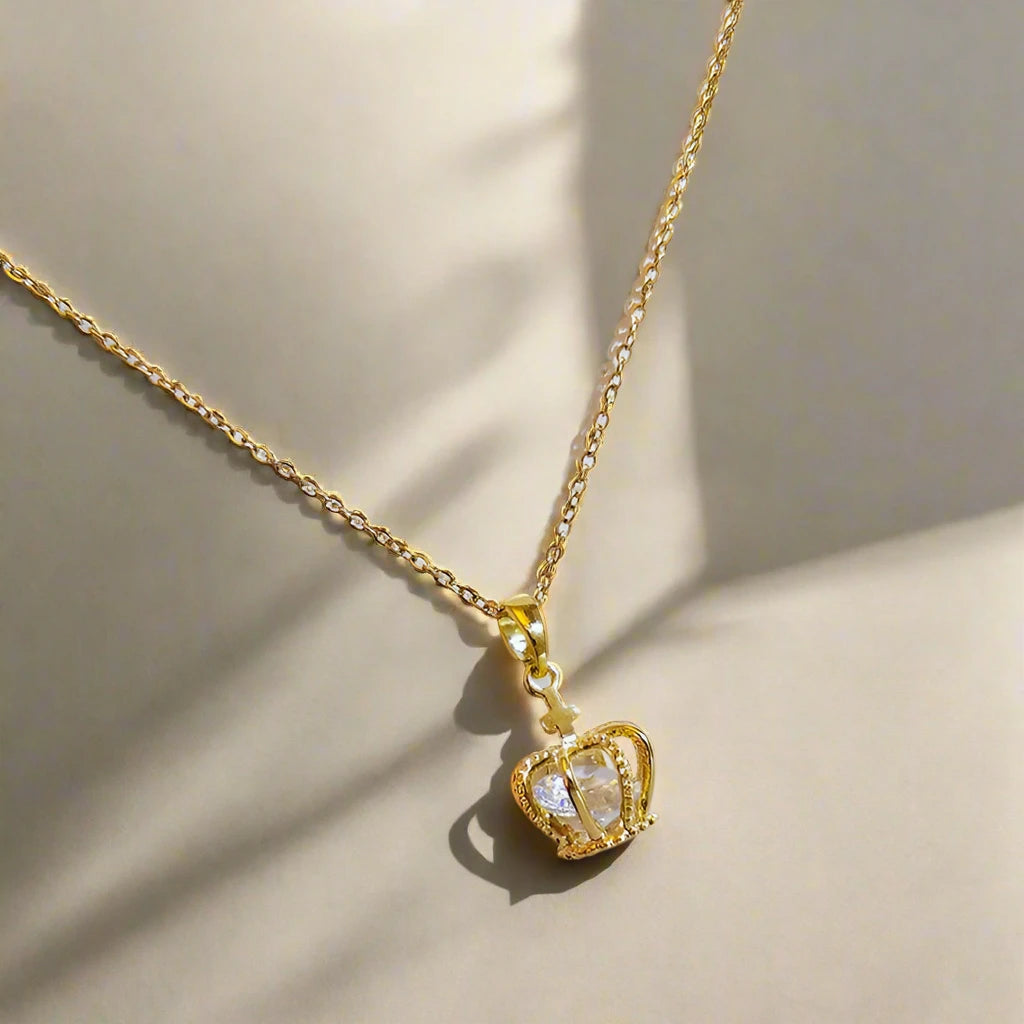 Gold necklace with a crown pendant on a white background
