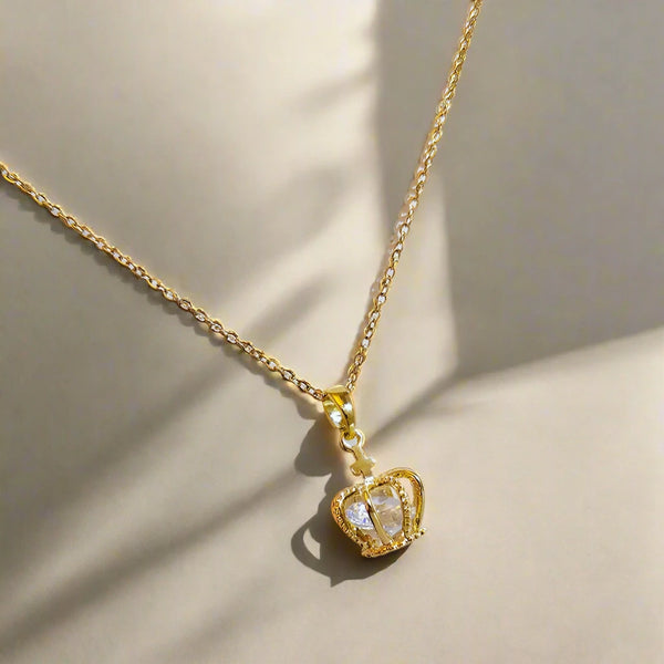 Gold necklace with a crown pendant on a white background